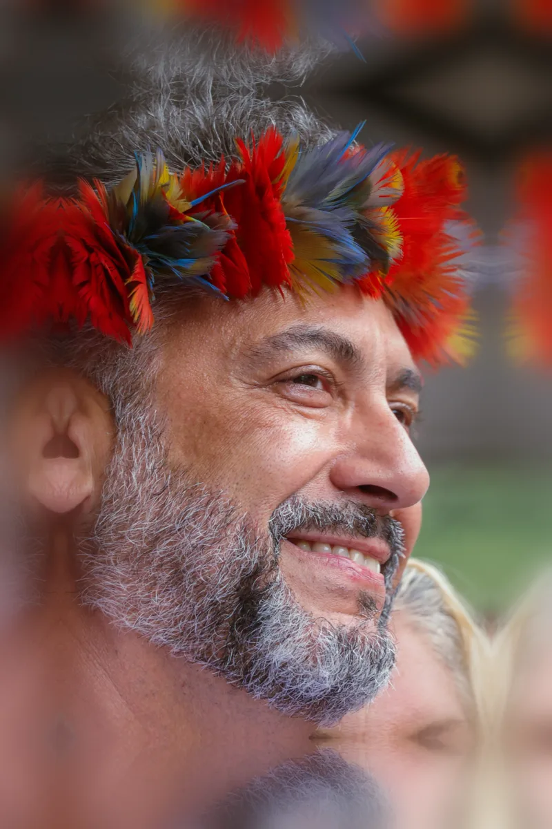 Clécio com cocar indígena, sorrindo, em encontro com a população